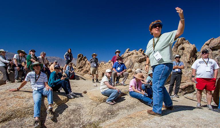 Students and faculty sitting and discussing on top of a mountain.